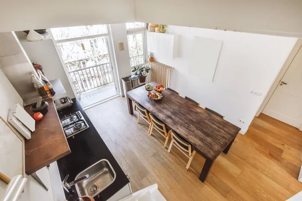 Top view of bright kitchen and dining room interior with balcony doors in modern apartment during daytime