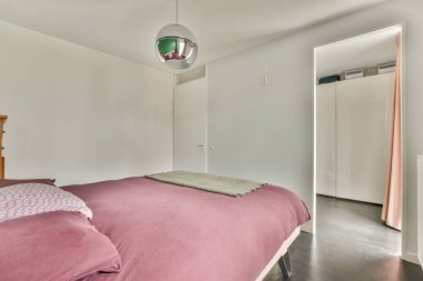 Geniş, parlak, minimalist bir lambası ve geniş bir panoramik penceresi olan bir yatak odası.