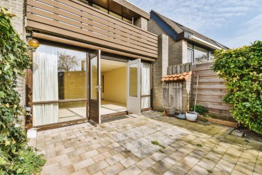 Oturma alanı ve ahşap çitlerin yanındaki küçük bahçesi olan düzgün asfaltlı bir avlu.