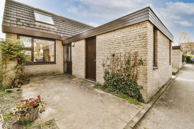 Tabelaları, arabaları, kaldırımları ve ahşap kapıları olan tuğla binanın önü daireye çıkıyor.