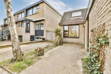 Tabelaları, arabaları, kaldırımları ve ahşap kapıları olan tuğla binanın önü daireye çıkıyor.