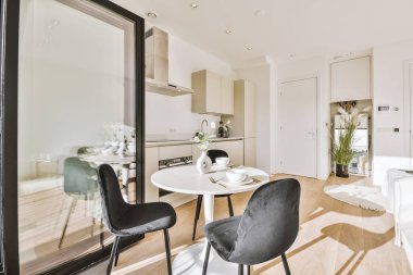 Home interior design of modern apartment with open kitchen in minimalist style and spacious dining zone with table and chairs