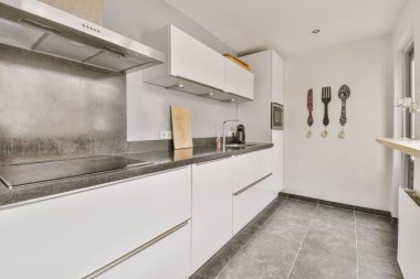 Çağdaş açık mutfak malzemeleri ve tavan altındaki karanlık dolaplarla aydınlık ahşap kirişlerle donatılmış