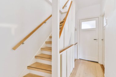 Beyaz spiral merdiven, çağdaş evi ahşap zemin ve beyaz duvarlarla birbirine bağlıyor.