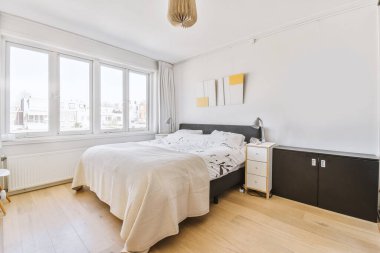 Yumuşak renkli yastıkları ve yeşil duvarı ve şık yatak odasındaki penceresi olan lüks bir yatak.