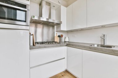 Minimalist tarzı beyaz mobilyalı, lavabolu ve sobalı bir ev mutfağı.