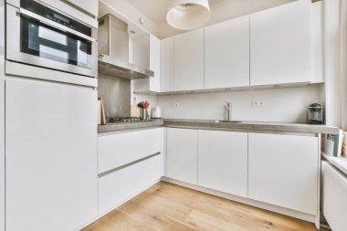 Minimalist tarzı beyaz mobilyalı, lavabolu ve sobalı bir ev mutfağı.