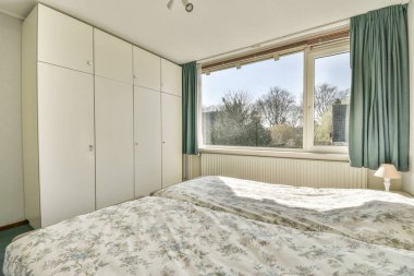 Yatak odasının iç tasarımı, yatak odası ve ahşap gardırop modern dairenin penceresinin kenarına yerleştirilmiş.