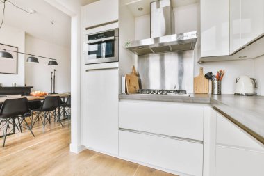 Minimalist tarzı beyaz mobilyalı, lavabolu ve sobalı bir ev mutfağı.