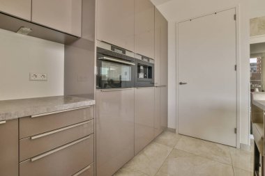 Beyaz dolaplar, ahşap mutfak tezgahı ve oturma odasında yemek masası.