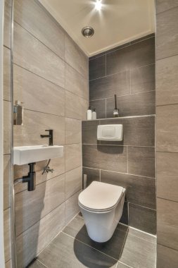 Banyonun minimalist iç kısımlarına asılmış siyah duvar ve üst rafta çiçekler var.