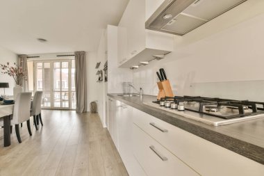 Beyaz duvarları ve fayanslı zemini olan geniş, parlak bir mutfak.