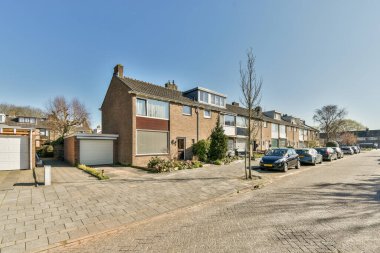 Arabaları, ağaçları ve fenerleri olan boş bir kaldırımdan panorama manzaralı evler.