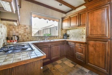 Fragment of interior of brown narrow home kitchen with minimalist style white furniture with sink and stove
