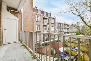 Dar tuğlalı balkon, metal parmaklıklar ve kapı.