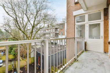 Dar tuğlalı balkon, metal parmaklıklar ve kapı.