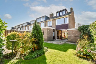 Oturma alanı ve ahşap çitlerin yanındaki küçük bahçesi olan düzgün asfaltlı bir avlu.