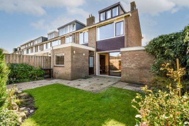 Oturma alanı ve ahşap çitlerin yanındaki küçük bahçesi olan düzgün asfaltlı bir avlu.