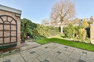 Oturma alanı ve ahşap çitlerin yanındaki küçük bahçesi olan düzgün asfaltlı bir avlu.