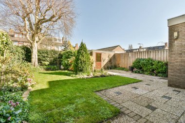 Oturma alanı ve ahşap çitlerin yanındaki küçük bahçesi olan düzgün asfaltlı bir avlu.