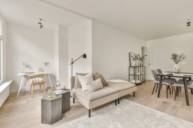 Modern apartmandaki dekorasyonlu ve televizyonlu, rahat koltuğun yanına yerleştirilmiş eski püskü ahşap masa.