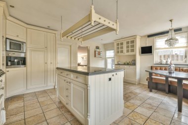 Gündüz vakti modern bir dairede yemek odasının yakınında modern dolaplar ve aletlerle donatılmış aydınlık mutfağın içi.