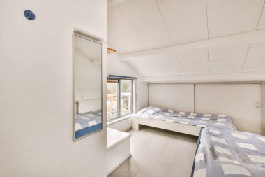 Süslü battaniyesiz rahat yataklar. Yatak odasında askı olan cam kapının yanına yerleştirilmiş.