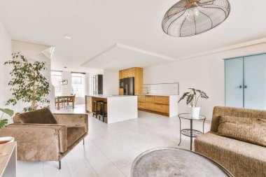 Çağdaş açık mutfak, yemek masası seti ve ferah odada gri kanepe.