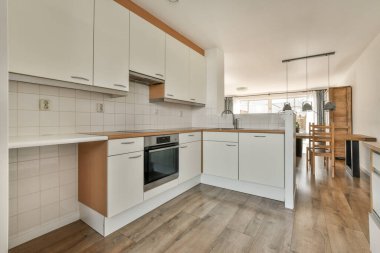 Günümüz minimalist tasarımı. Hafif stüdyo dairesinin ahşap masası ve oturma odası ile beyaz duvarları ve parke zemini arasında yemek masası ve sandalyeleri var.