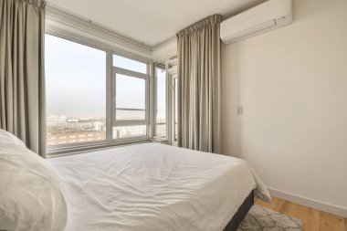 Pencerenin yanındaki konforlu yatak odası, güncel dairenin aydınlık yatak odası.