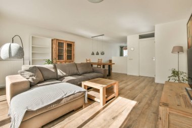 Günümüz minimalist tasarımı. Hafif stüdyo dairesinin ahşap masası ve oturma odası ile beyaz duvarları ve parke zemini arasında yemek masası ve sandalyeleri var.