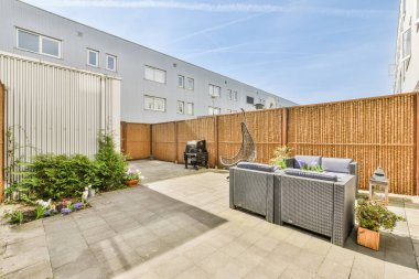 Oturma alanı ve ahşap çitlerin yanındaki küçük bahçesi olan düzgün asfaltlı bir avlu.