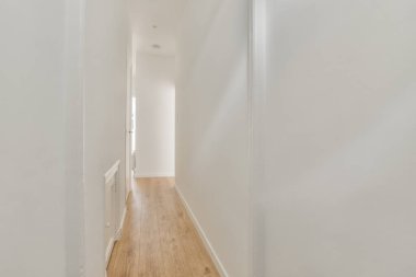 Dar koridorun içinde bir sürü kapı ve beyaz duvarlarda klasik resim var.