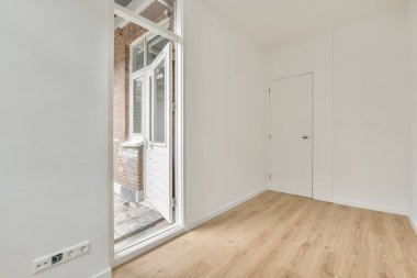 Evdeki boş ışık odasında, beyaz duvardaki plastik pencere ve radyatör.