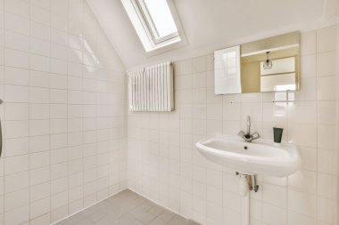 Cam duşlu küvet lavabonun yanında ve aynada beyaz fayans duvarlı küçük bir banyoda.