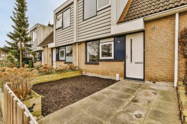 Oturma alanı ve ahşap çitlerin yanındaki küçük bahçesi olan düzgün asfaltlı bir avlu.