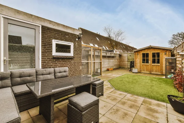 Oturma alanı ve ahşap çitlerin yanındaki küçük bahçesi olan düzgün asfaltlı bir avlu.