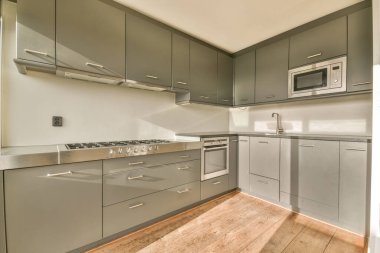 Pencereleri ve ahşap parke zemini olan boş beyaz mutfağın içi.