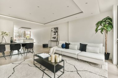 Günümüz minimalist tasarımı. Hafif stüdyo dairesinin ahşap masası ve oturma odası ile beyaz duvarları ve parke zemini arasında yemek masası ve sandalyeleri var.