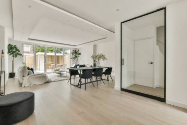 Günümüz minimalist tasarımı. Hafif stüdyo dairesinin ahşap masası ve oturma odası ile beyaz duvarları ve parke zemini arasında yemek masası ve sandalyeleri var.