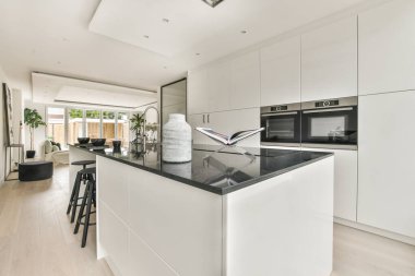 Günümüz minimalist tasarımı. Hafif stüdyo dairesinin ahşap masası ve oturma odası ile beyaz duvarları ve parke zemini arasında yemek masası ve sandalyeleri var.