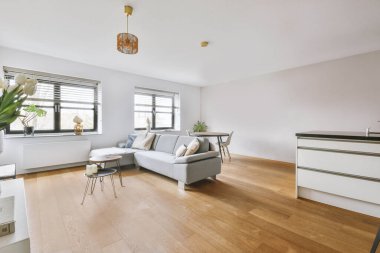 Çağdaş açık mutfak, yemek masası seti ve ferah odada gri kanepe.