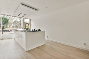 Günümüz minimalist tasarımı. Hafif stüdyo dairesinin ahşap masası ve oturma odası ile beyaz duvarları ve parke zemini arasında yemek masası ve sandalyeleri var.