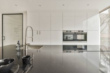 Minimalist tarzı beyaz mobilyalı, lavabolu ve sobalı bir ev mutfağı.