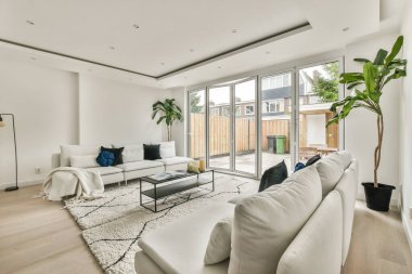 Günümüz minimalist tasarımı. Hafif stüdyo dairesinin ahşap masası ve oturma odası ile beyaz duvarları ve parke zemini arasında yemek masası ve sandalyeleri var.