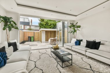 Günümüz minimalist tasarımı. Hafif stüdyo dairesinin ahşap masası ve oturma odası ile beyaz duvarları ve parke zemini arasında yemek masası ve sandalyeleri var.