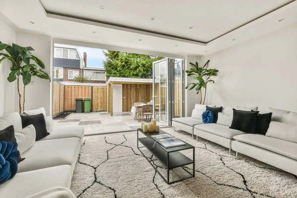 Günümüz minimalist tasarımı. Hafif stüdyo dairesinin ahşap masası ve oturma odası ile beyaz duvarları ve parke zemini arasında yemek masası ve sandalyeleri var.