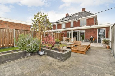 Oturma alanı ve ahşap çitlerin yanındaki küçük bahçesi olan düzgün asfaltlı bir avlu.