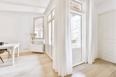 Saksı bitkilerinin yanındaki şık bitkilerin altındaki sandalyeli masa ve çağdaş düzlükte balkon kapısı ve pencerelere karşı çerçeveli resim