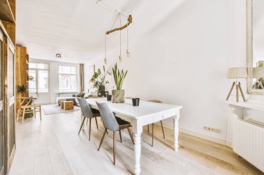 TV 'nin yanındaki koltuklar ve masa, çağdaş apartmandaki geniş odalı yemek alanına karşıdır.
